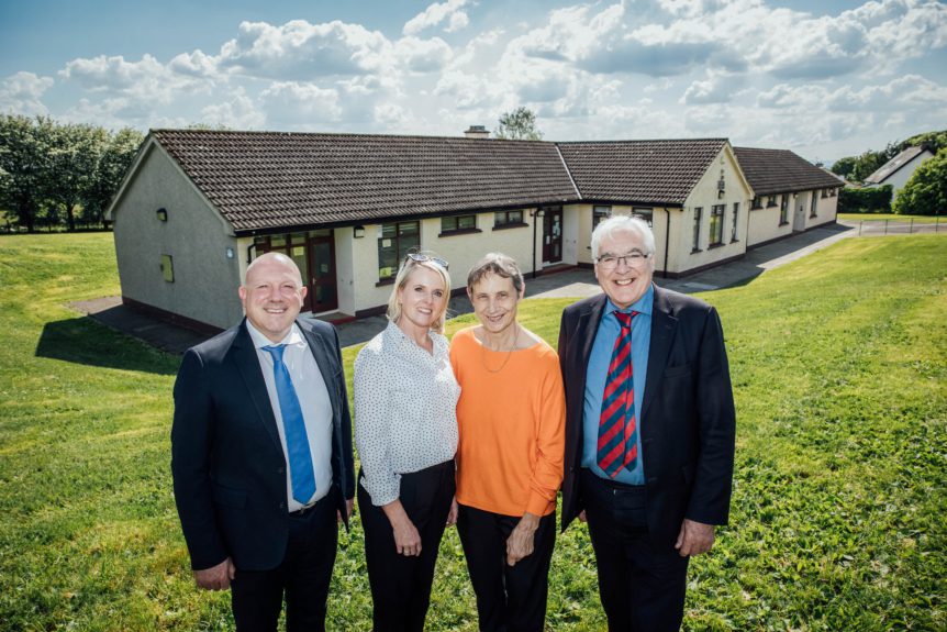 A picture of 4 people at the announcement of the transfer of the school's patronage.